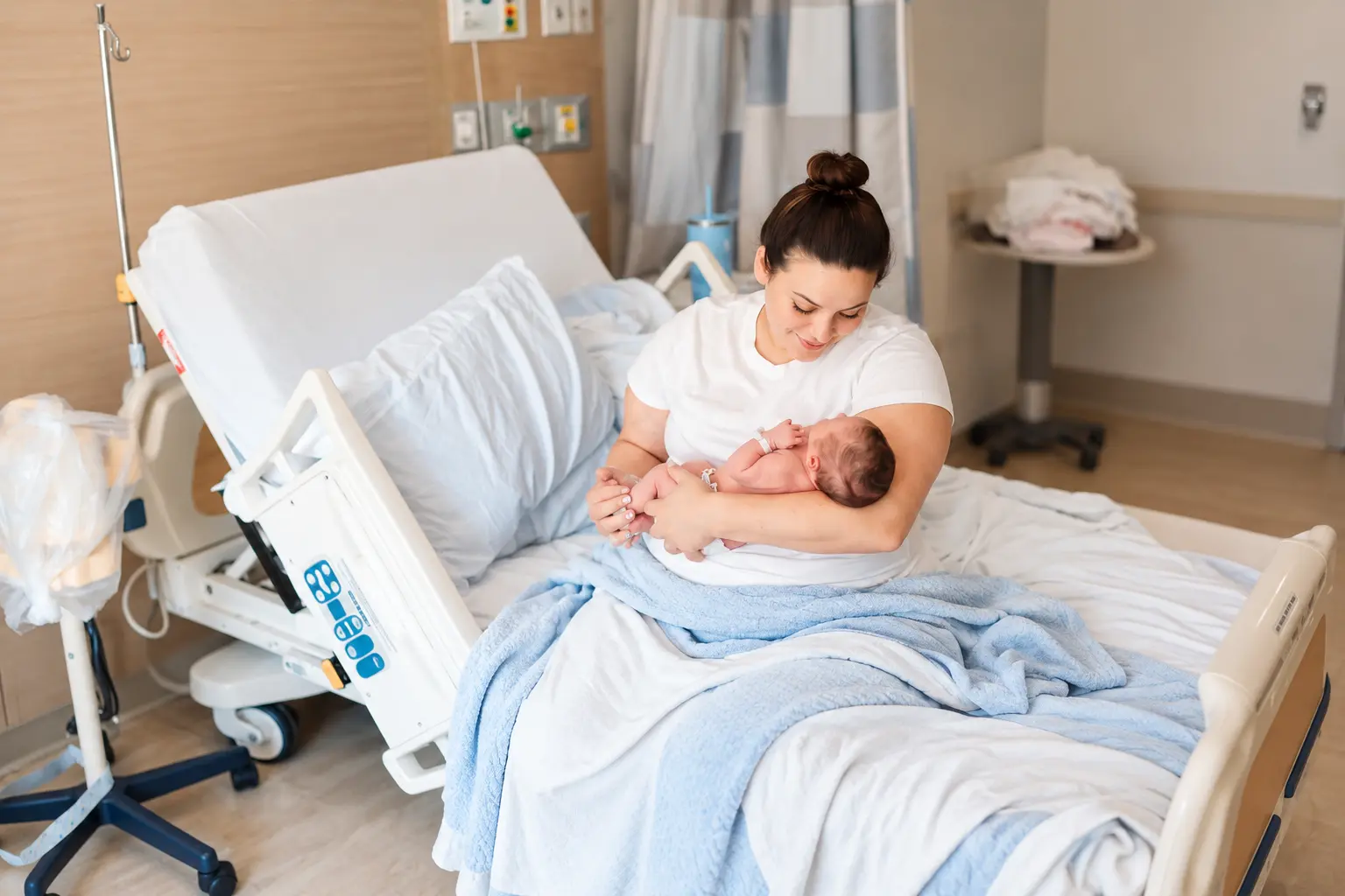 An adult holding a relaxed newborn close